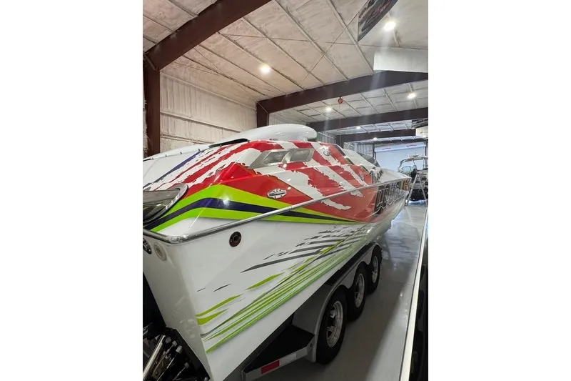 Slide: The Image of 1999 Skater 32B powerboat with vibrant red, green, and white graphics in a storage facility. - 2