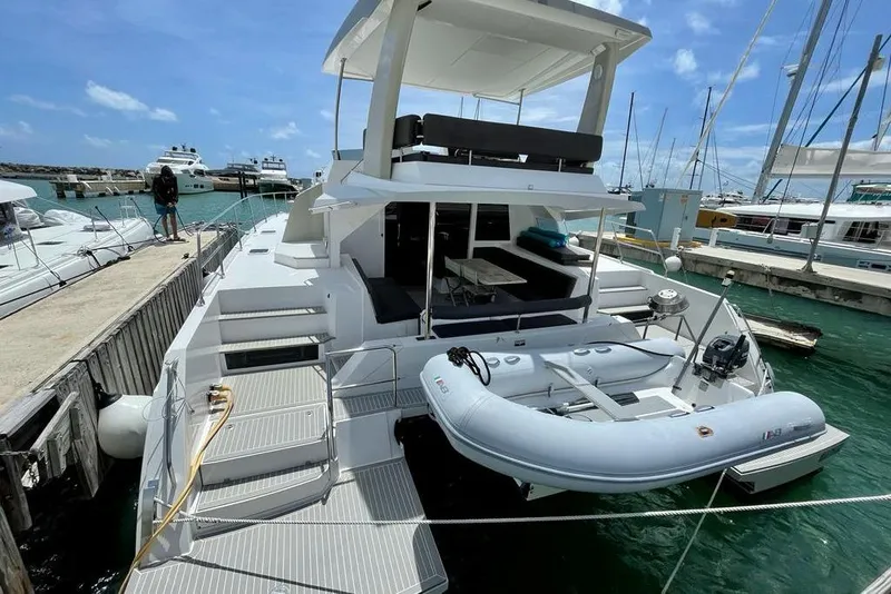 Slide: The Image of 2019 Nautitech 47 Power yacht docked with inflatable boat, showcasing spacious deck and seating area. - 15