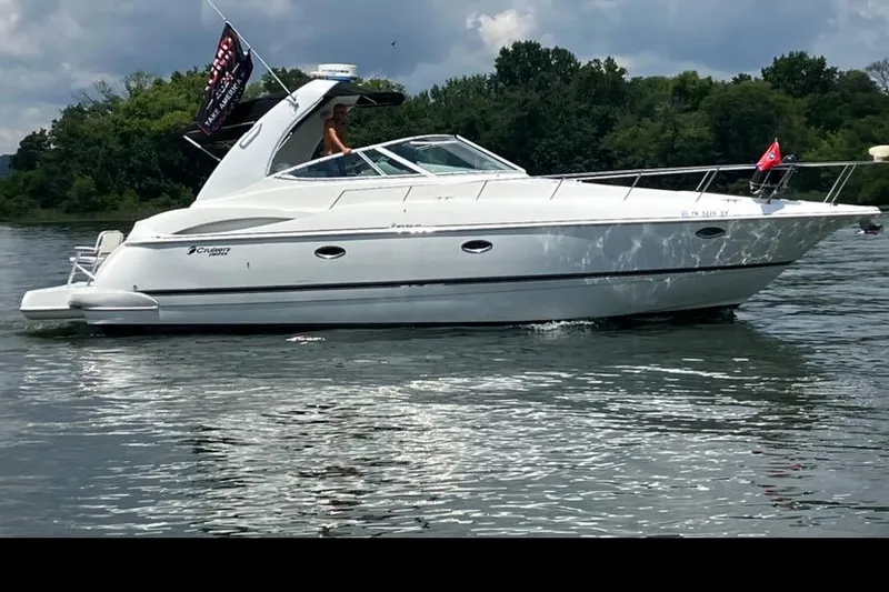 Slide: The Image of 2001 Cruisers Yachts 3672 Express on a serene lake with lush green background. - 2