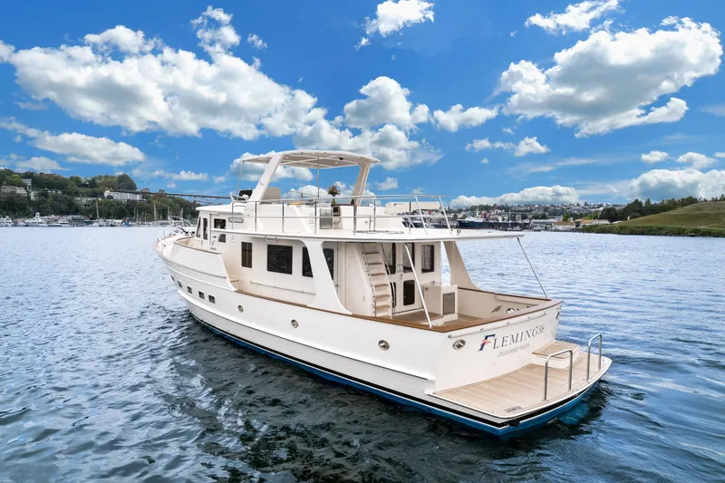 Slide: The Image of 2024 Fleming 58 Pilothouse yacht on calm water under a partly cloudy sky. - 4