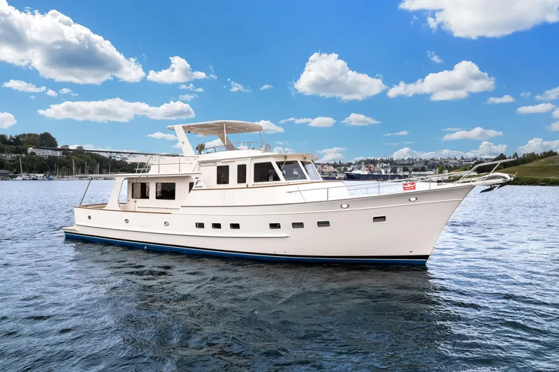Slide: The Image of 2024 Fleming 58 Pilothouse yacht cruising on a calm, scenic waterway under a blue sky. - 6