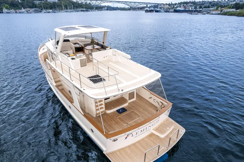 Slide: The Image of 2024 Fleming 58 Pilothouse yacht cruising on a serene lake with scenic bridge view. - 7