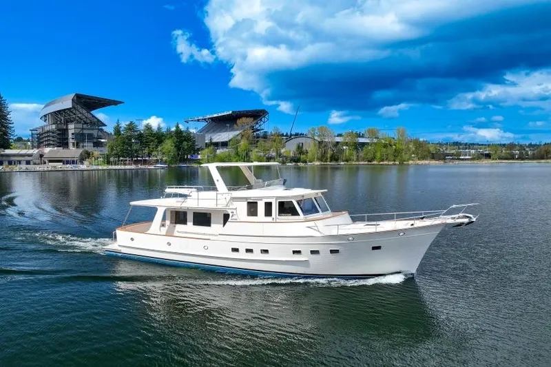 The Image of 2024 Fleming 58 Pilothouse yacht cruising on a scenic lake with stadium backdrop. - 0