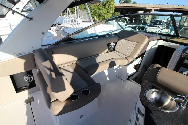 Slide: The Image of 2015 Regal 32 Express boat interior with seating and sink, docked near other boats. - 12