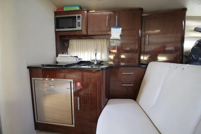 Slide: The Image of 2015 Regal 32 Express yacht interior with kitchenette, featuring microwave, sink, and wooden cabinetry. - 17