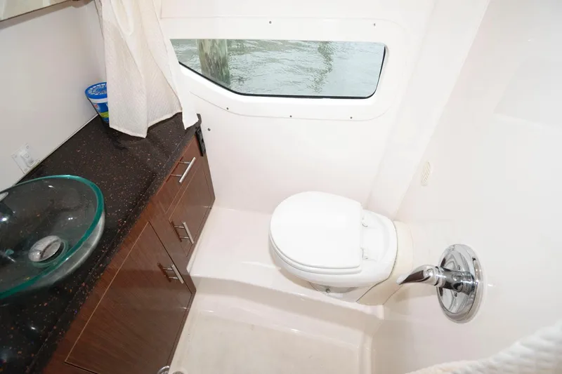 Slide: The Image of 2015 Regal 32 Express boat bathroom with sink, toilet, and window. - 21