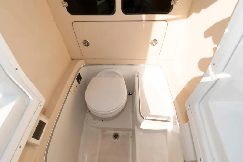 Slide: The Image of 2013 Chris-Craft Catalina 26 boat bathroom with toilet and storage compartment. - 16