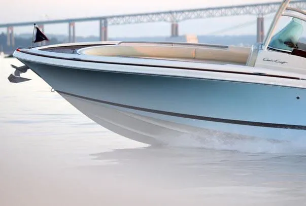 Slide: The Image of 2013 Chris-Craft Catalina 26 helm with luxurious seating and modern controls, docked by a scenic river. - 5