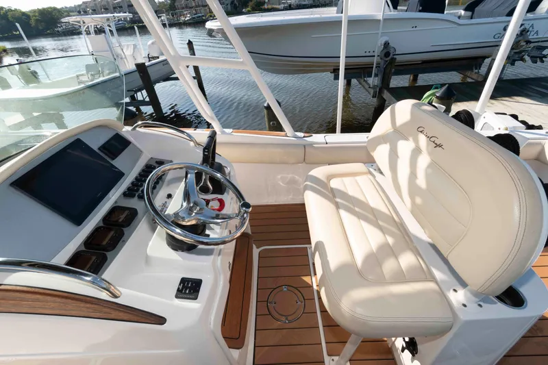Slide: The Image of 2013 Chris-Craft Catalina 26 boat interior with steering wheel and seating, docked by the water. - 9