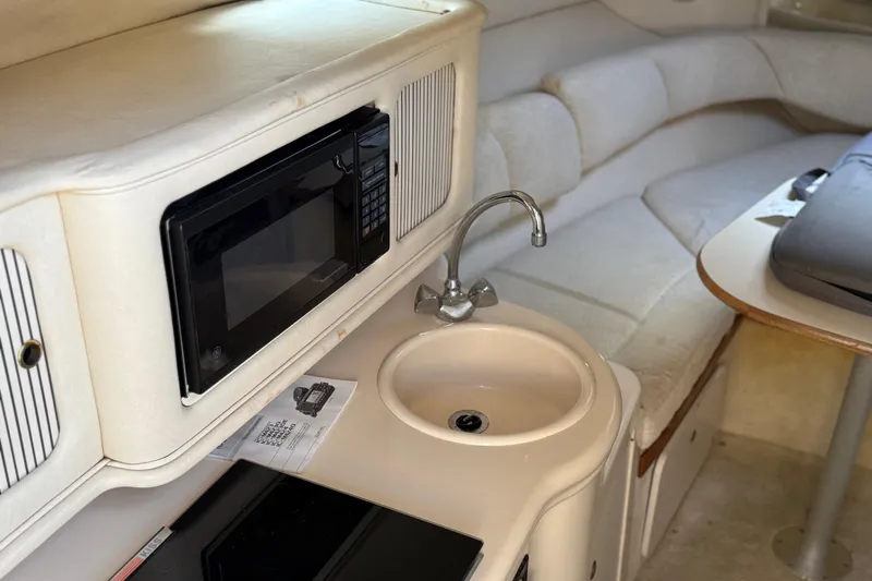 Slide: The Image of 2001 Sea Ray 260 Sundancer interior with kitchenette, featuring a microwave, sink, and seating area. - 16