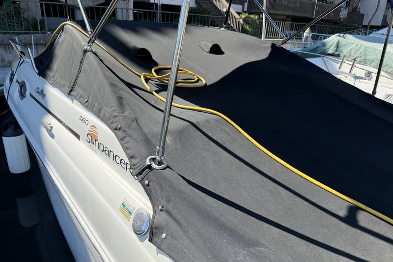 Slide: The Image of 2001 Sea Ray 260 Sundancer boat with black cover and yellow rope on deck. - 2