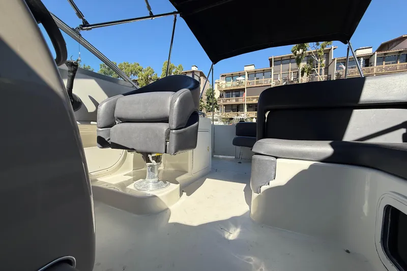 Slide: The Image of 2001 Sea Ray 260 Sundancer boat interior with seating and canopy, docked near buildings. - 23