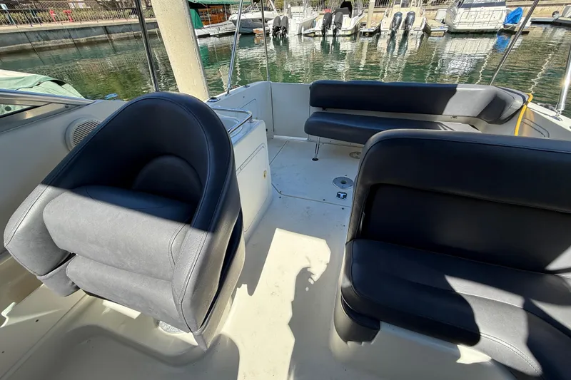 Slide: The Image of 2001 Sea Ray 260 Sundancer boat interior with black seating and marina view. - 33