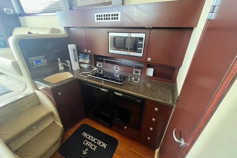 Slide: The Image of 2007 Sea Ray 36 Sedan Bridge kitchen with microwave, sink, and dark wood cabinetry. - 29
