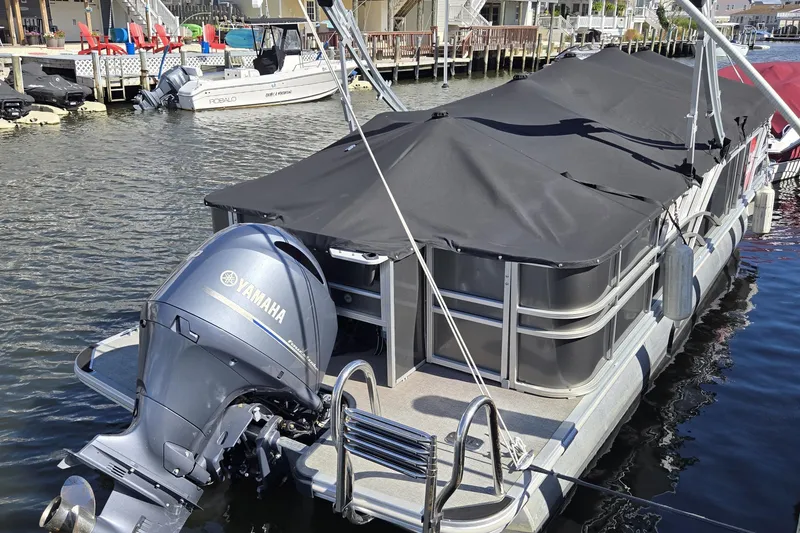Slide: The Image of 2022 Sylvan L3 Party Fish pontoon boat with Yamaha outboard motor, docked in a marina. - 2