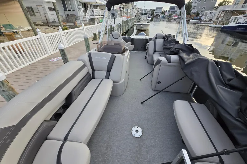 Slide: The Image of 2022 Sylvan L3 Party Fish pontoon boat with spacious seating, docked by waterfront homes. - 5