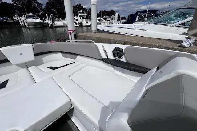 Slide: The Image of 2023 Four Winns H290 boat interior with white seating at a marina. - 12