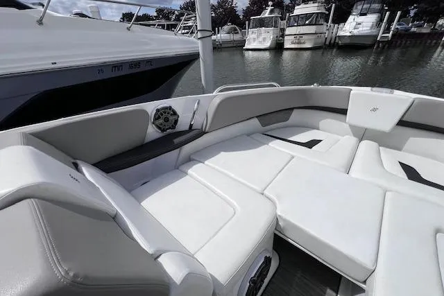 Slide: The Image of 2023 Four Winns H290 boat interior with white seating, docked at a marina. - 13