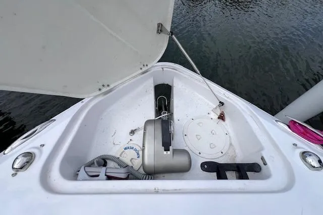 Slide: The Image of 2023 Four Winns H290 boat anchor compartment with open hatch, docked on water. - 16