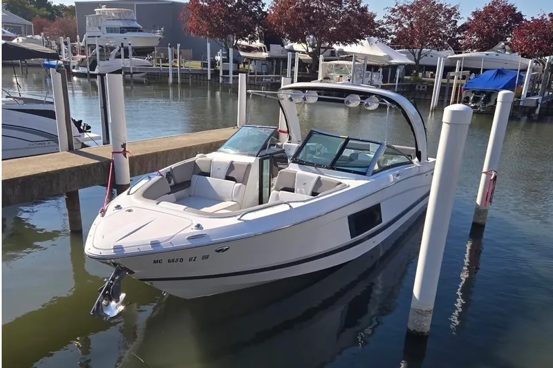 Slide: The Image of 2023 Four Winns H290 boat docked in a marina, surrounded by calm water. - 4