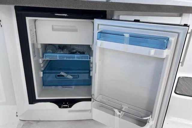 Slide: The Image of 2023 Four Winns H290 boat refrigerator with open door, showcasing interior storage compartments. - 45