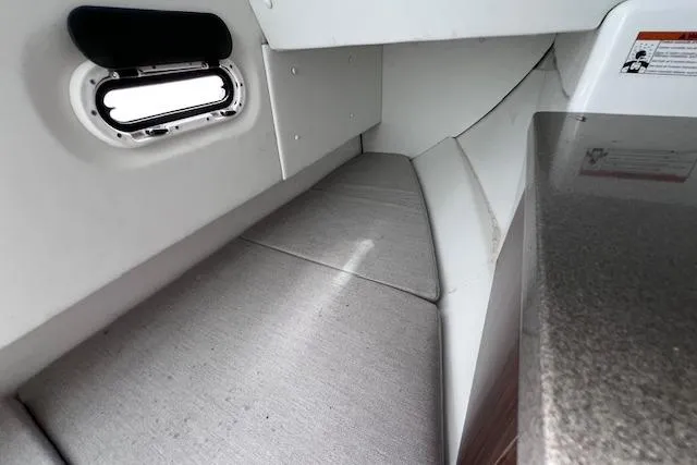 Slide: The Image of 2023 Four Winns H290 cabin interior with cushioned seating and small window. - 56