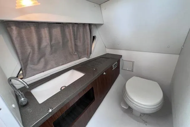 Slide: The Image of 2023 Four Winns H290 boat bathroom with sink, toilet, and curtain. - 57