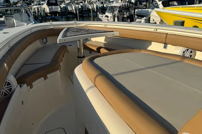 Slide: The Image of 2017 Scout 355 LXF boat interior with tan seating and table, docked at marina. - 27