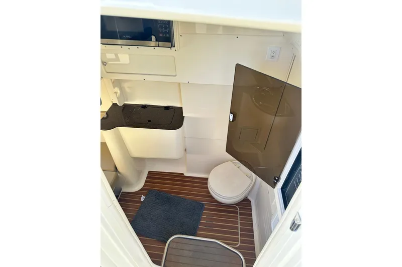 Slide: The Image of 2017 Scout 350 LXF boat interior with toilet and sink, featuring wood flooring. - 30
