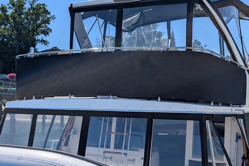 Slide: The Image of 1989 Bayliner 3888 Motoryacht with enclosed upper deck, docked near trees. - 11