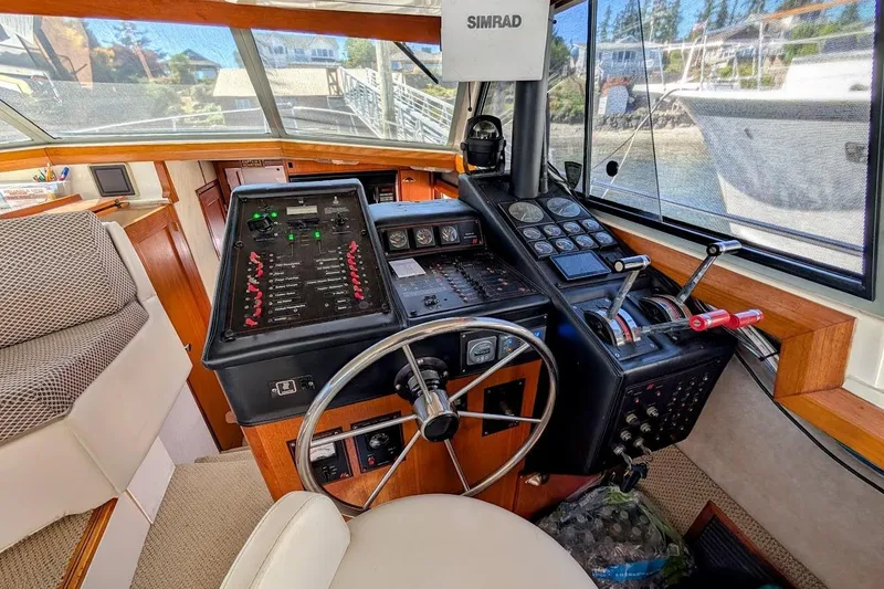 Slide: The Image of 1989 Bayliner 3888 Motoryacht helm with steering wheel, control panel, and navigation equipment. - 13