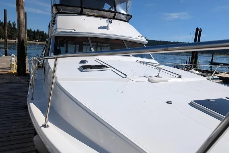 Slide: The Image of 1989 Bayliner 3888 Motoryacht docked by a scenic waterfront under clear blue skies. - 3