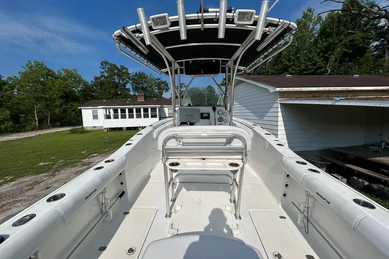 Slide: The Image of 2008 Sea Fox 256 Commander boat with T-top, docked near white house and trees. - 5