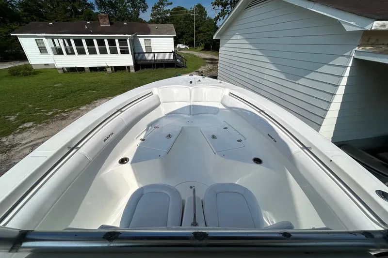 Slide: The Image of 2008 Sea Fox 256 Commander boat interior, white seating, parked near a house. - 6