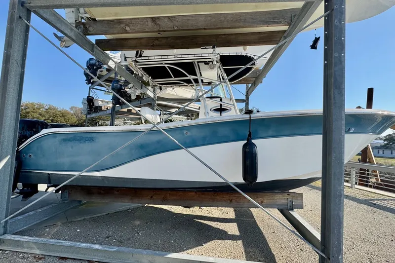 Slide: The Image of 2008 Sea Fox 256 Commander boat on a lift, blue and white hull, outdoor setting. - 7