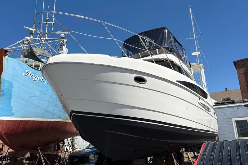 Slide: The Image of 2005 Meridian 368 Motoryacht on dry dock, alongside a blue vessel, under clear sky. - 6