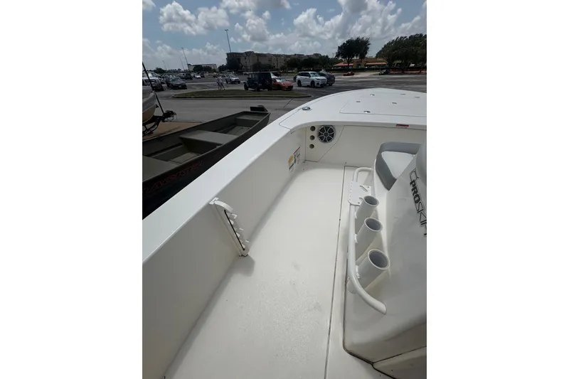 Slide: The Image of 2026 Mako 18 Pro Skiff boat interior with rod holders and seating, parked outdoors. - 19