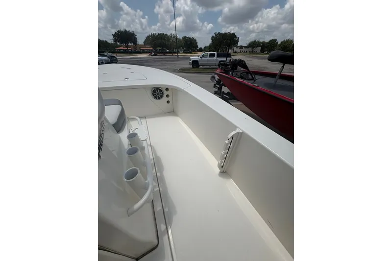 Slide: The Image of 2026 Mako 18 Pro Skiff interior with rod holders and seating, parked outdoors. - 21