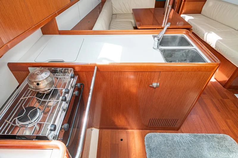 Slide: The Image of Interior of 2011 Beneteau Oceanis 37 yacht, featuring a compact kitchen with stove and sink. - 18