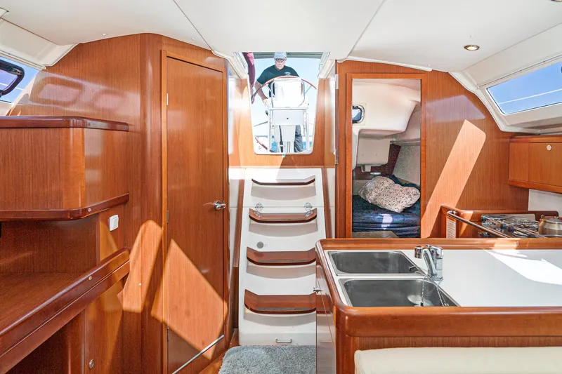 Slide: The Image of Interior of 2011 Beneteau Oceanis 37 sailboat, featuring wood finish and compact kitchen area. - 20