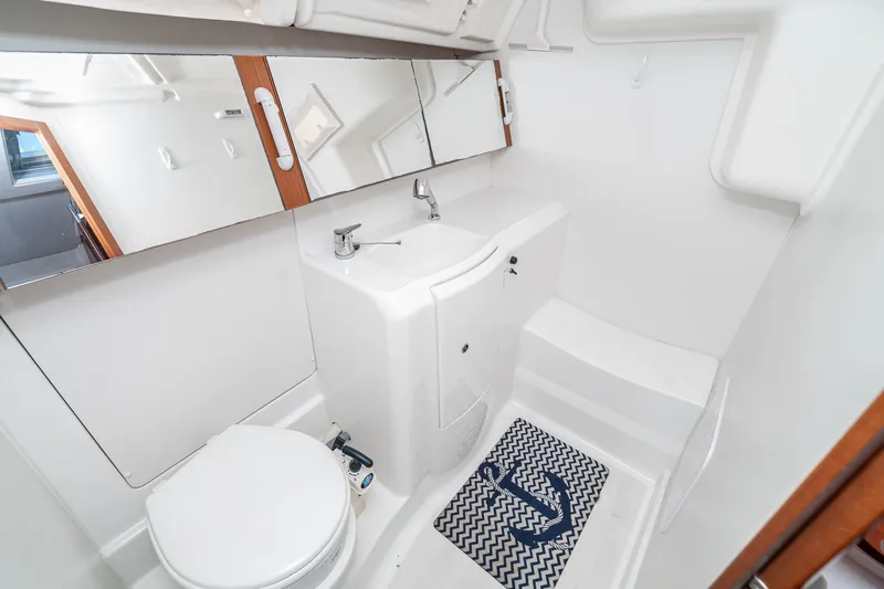 Slide: The Image of 2011 Beneteau Oceanis 37 yacht bathroom with white fixtures and nautical-themed mat. - 27