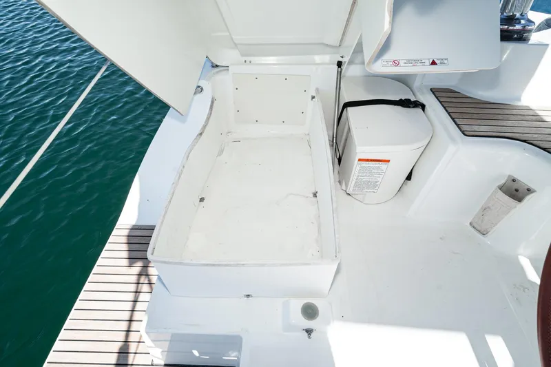 Slide: The Image of Beneteau Oceanis 37 (2011) cockpit storage area with open hatch, docked on calm water. - 38