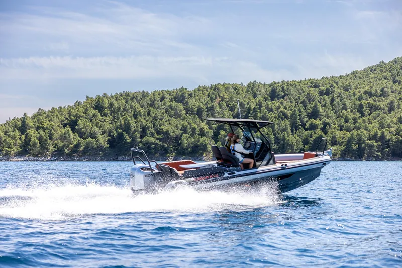 The Image of 2026 Highfield ADV7 boat cruising on blue water near a forested shoreline. - 1