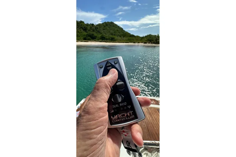 Slide: The Image of Hand holding yacht controller on Sunseeker Predator 62, 2009, near scenic shoreline. - 33