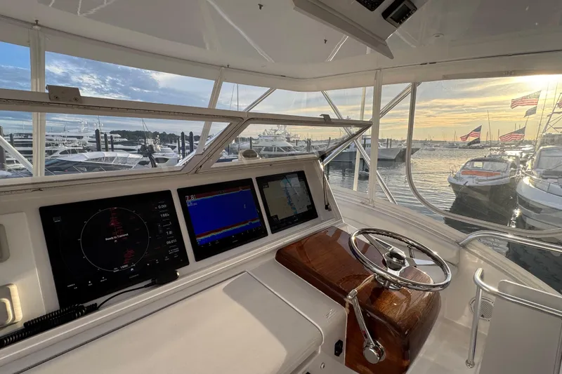 Slide: The Image of Helm of 2013 Hatteras GT54 yacht with navigation screens, overlooking marina at sunset. - 1