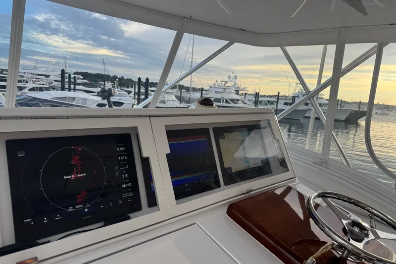 Slide: The Image of 2013 Hatteras GT54 yacht helm with navigation screens, docked at marina during sunset. - 2