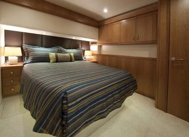 Slide: The Image of Manufacturer Provided Image: Luxurious bedroom interior of 2013 Hatteras GT54 yacht with striped bedding and wooden cabinets. - 11