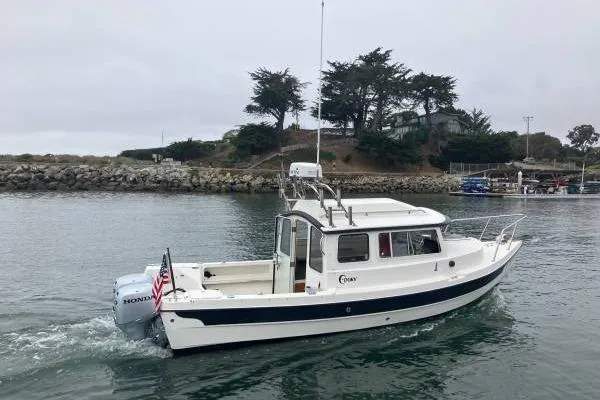 Slide: The Image of 2014 C-Dory 22 Cruiser boat on water near rocky shoreline. - 0