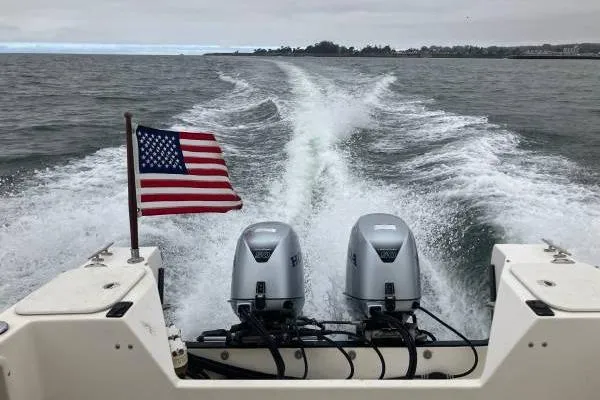 Slide: The Image of 2014 C-Dory 22 Cruiser with dual engines and American flag on open water. - 1