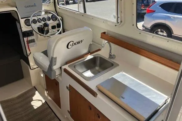 Slide: The Image of Interior of a 2014 C-Dory 22 Cruiser with steering wheel, sink, and storage. - 11
